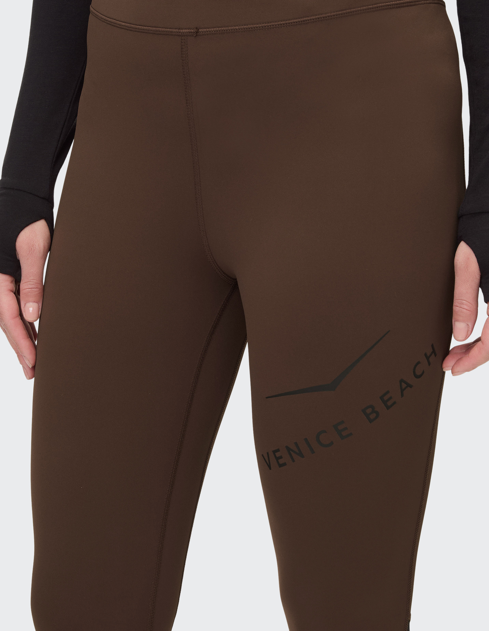 Braune Leggings mit hohem Bund, schmalem Schnitt und "Venice Beach"-Schriftzug seitlich am Oberschenkel, schlicht und modern.