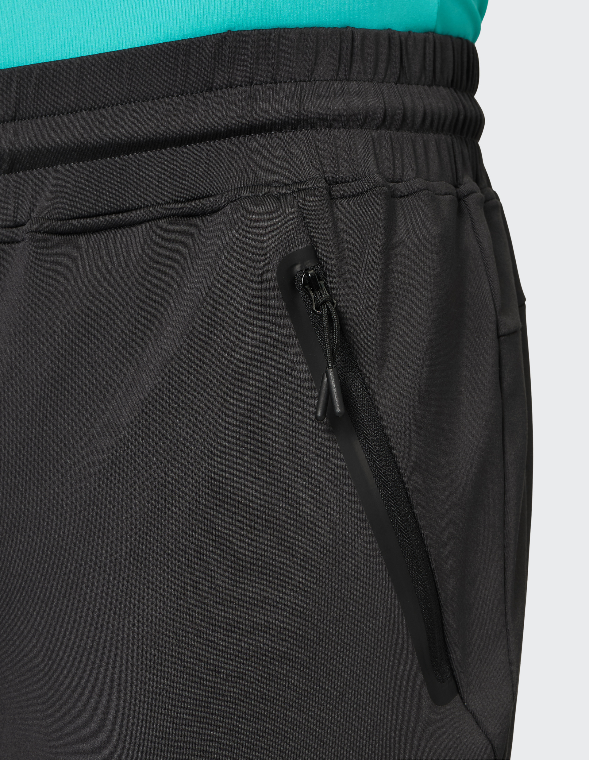 Schwarze Jogginghose mit elastischem Bund, Kordelzug, Seitentaschen mit Reißverschluss und kleinem orangefarbenem Detail am Bein.