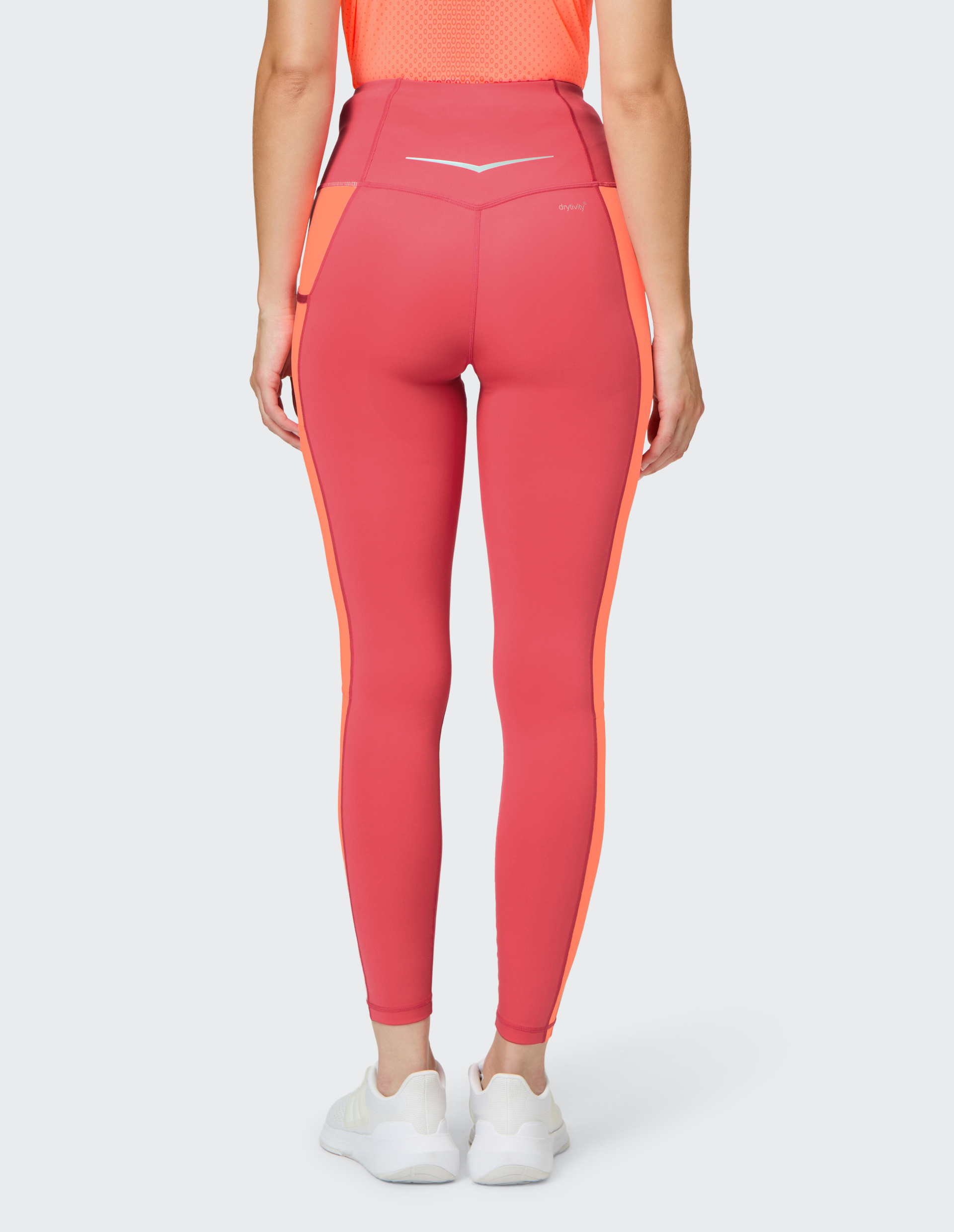 Rückansicht einer Person in pinken Sportleggings mit orangefarbenen Seitenstreifen, dazu weiße Sportschuhe und ein oranges Oberteil.