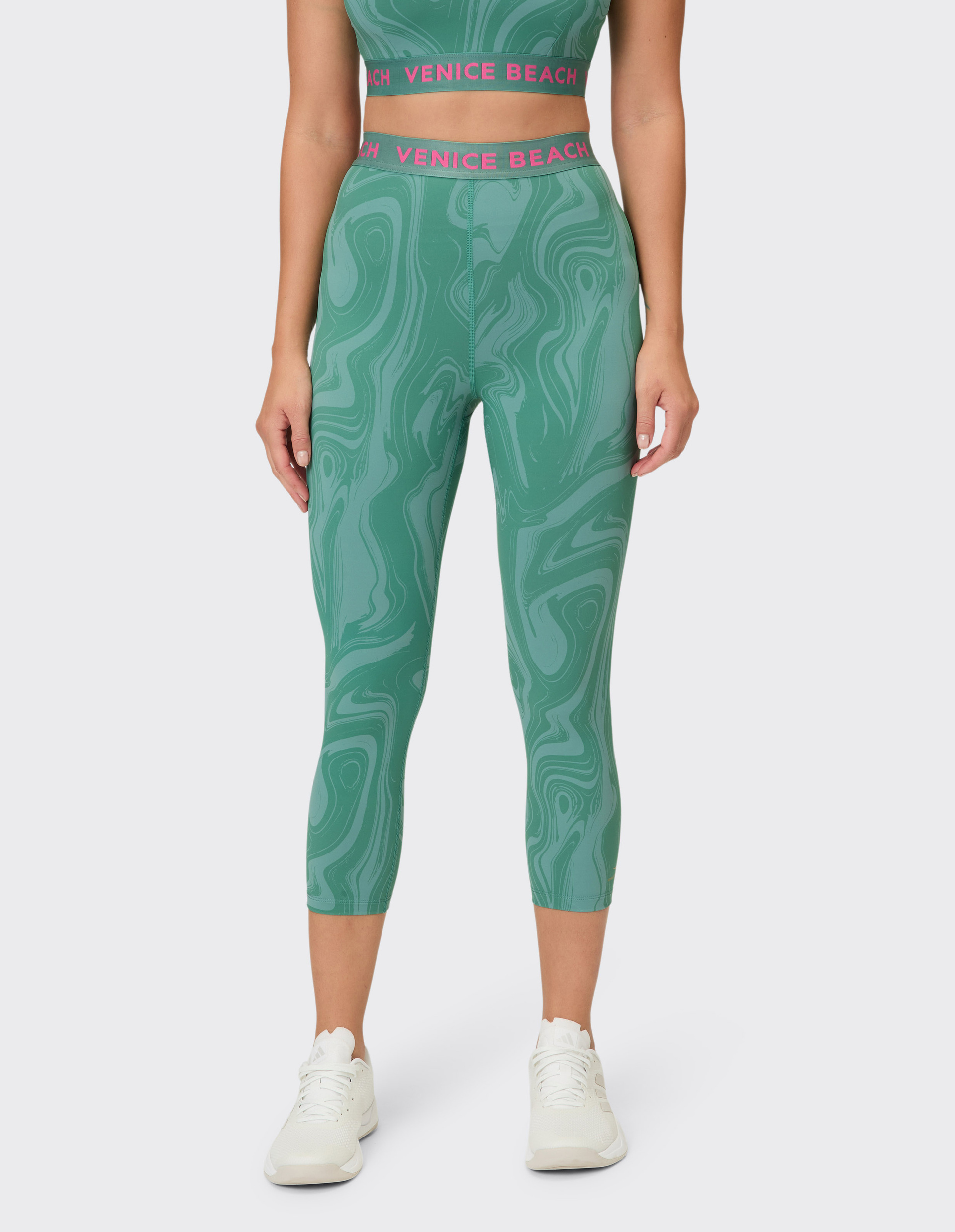 Grüne Capri-Leggings mit Marmormuster und pinkem Taillenbund mit Schriftzug.