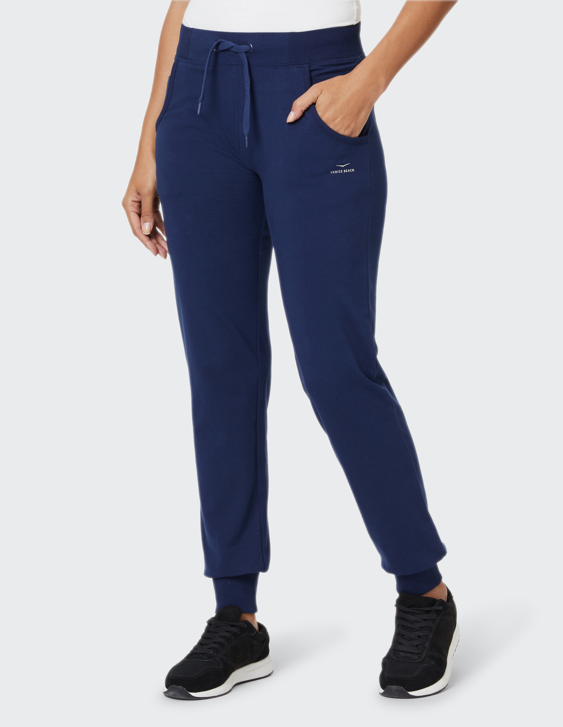Eine Person trägt eine dunkelblaue Jogginghose mit Kordelzug und einem kleinen Logo.