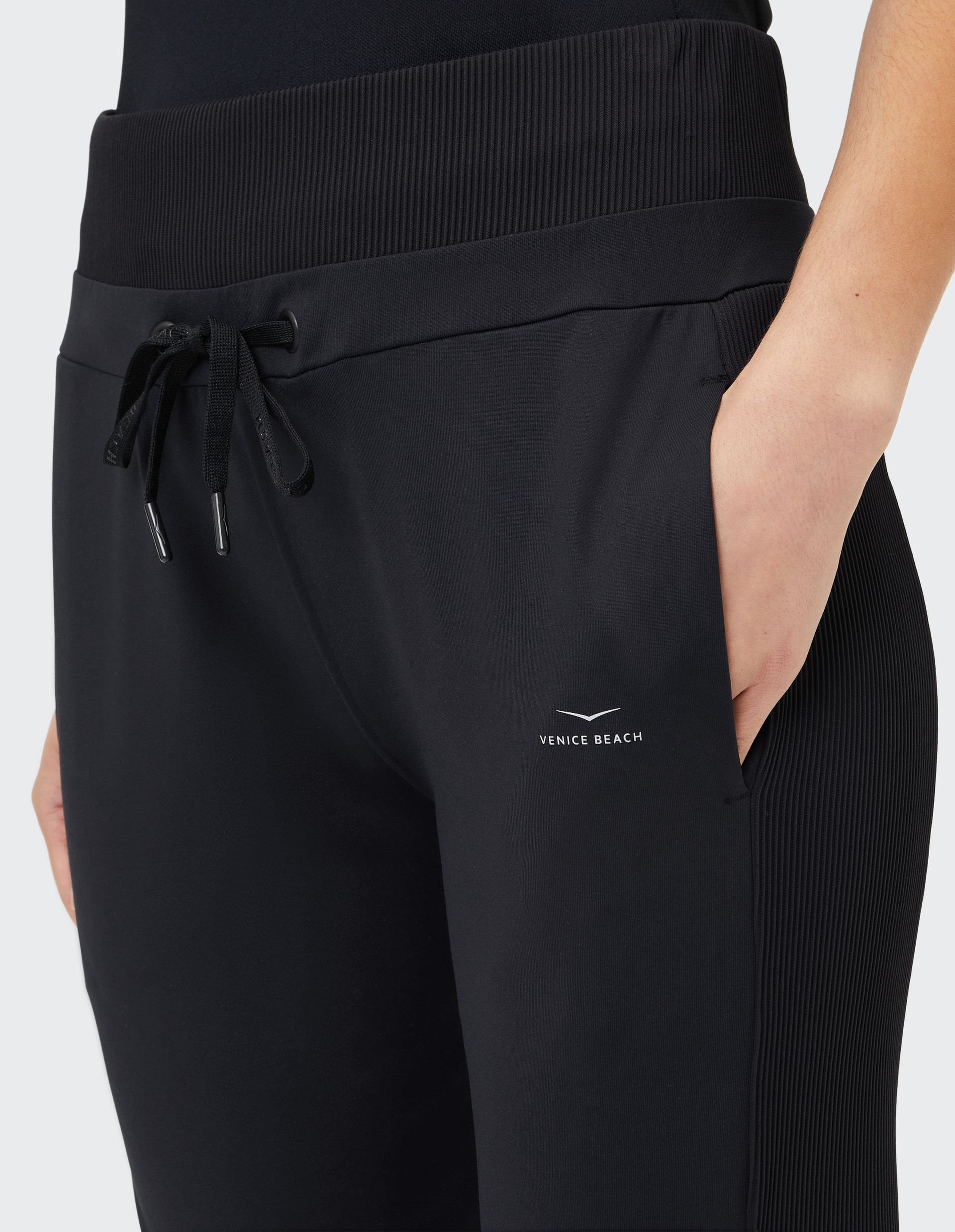Schwarze Jogginghose mit elastischem Bund und Kordelzug, seitliche Hand in der Tasche, Markenlogo "Venice Beach" auf dem Oberschenkel.