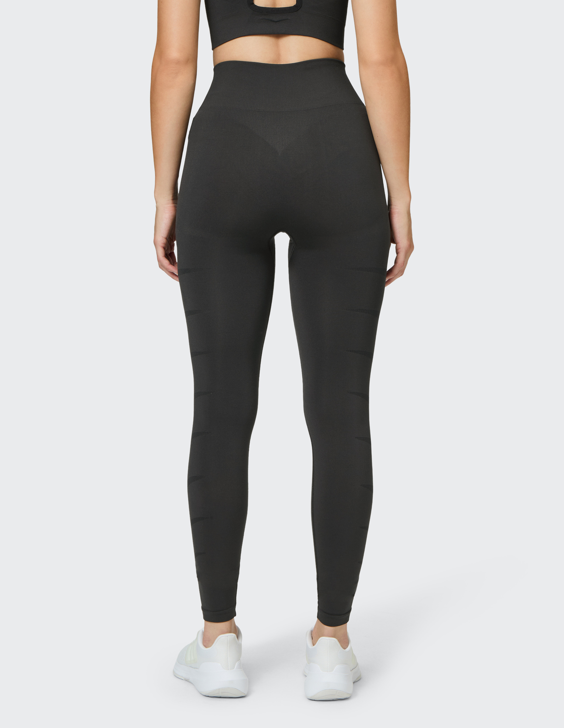 Schwarze, lange, nahtlose Sportleggings mit hohem Bund und subtilen, vertikalen Strukturrillen an den Beinen.