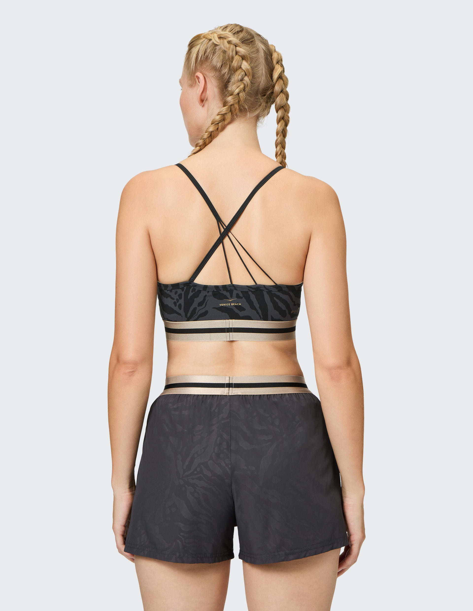 Schwarzer Sport-BH mit grauem Tiermuster, gekreuzten Trägern am Rücken und beige-grauem elastischem Saum.