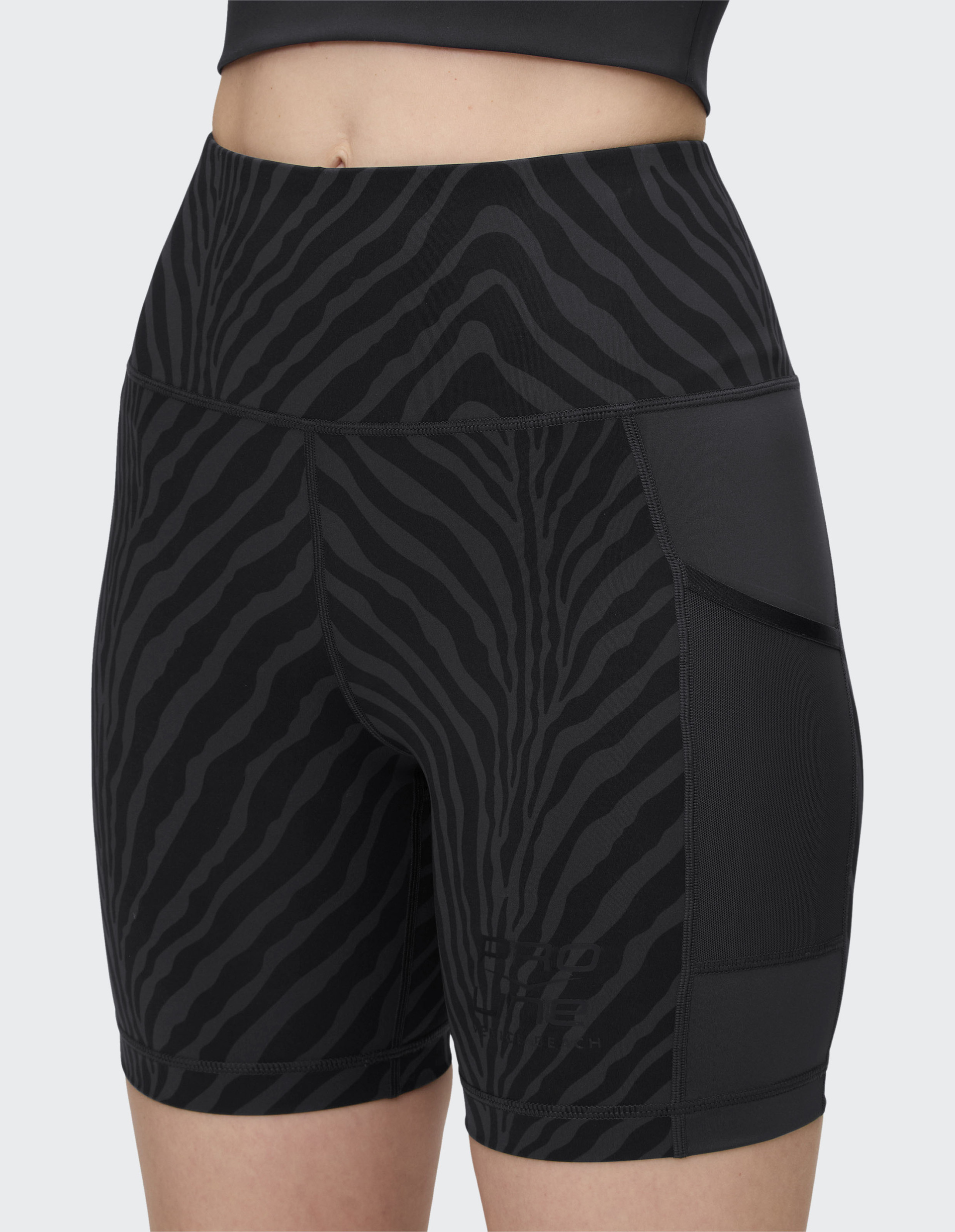 Schwarze Sport-Leggings mit hohem Bund und Zebramuster; eng anliegend mit seitlichen Netztaschen, vor grauem Hintergrund.