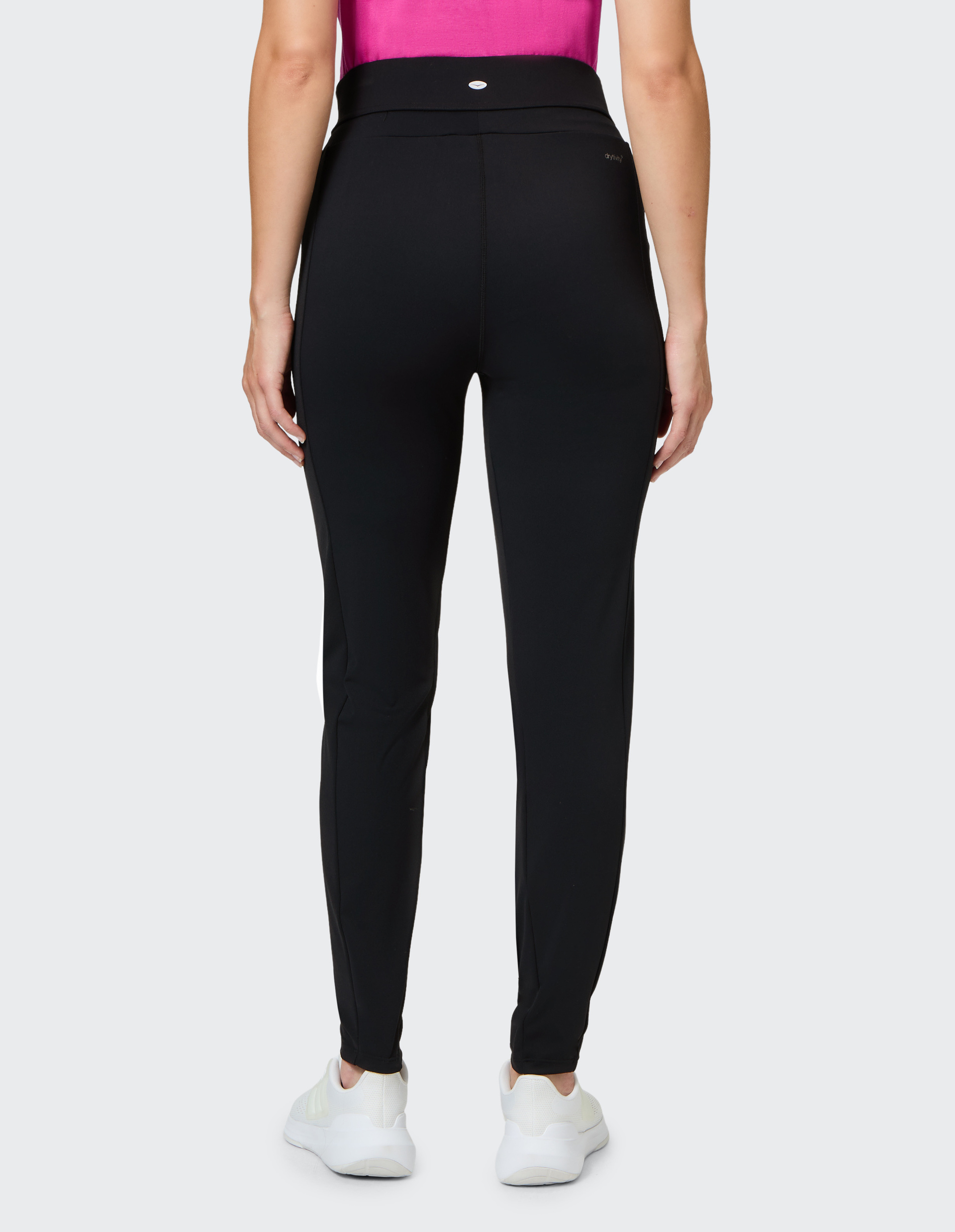 Person in schwarzer Hose und weißem Sneaker, Rückenansicht, trägt ein pinkes Oberteil vor grauem Hintergrund.