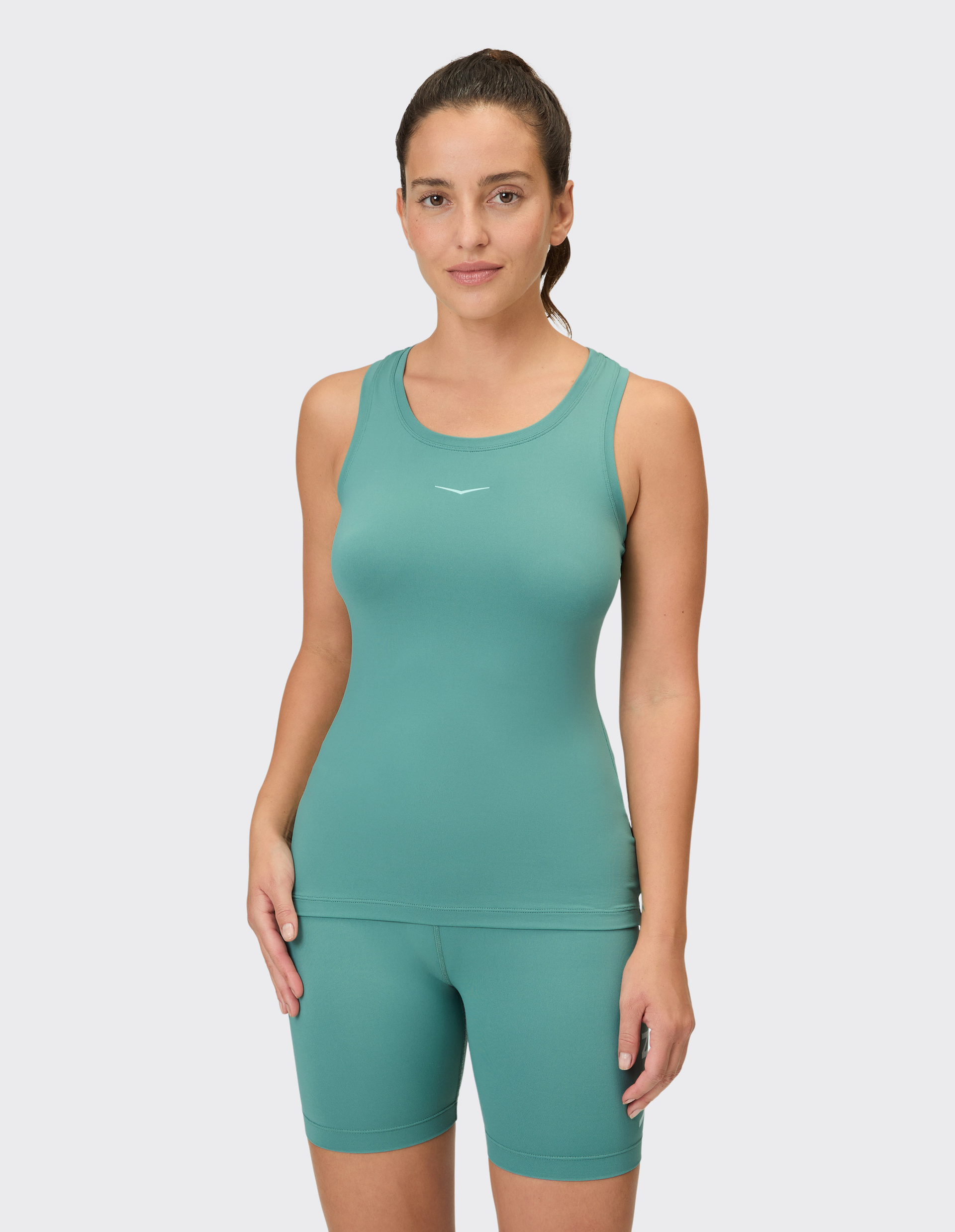 Ein Frau trägt ein smaragdgrünes, eng anliegendes Tanktop und passende Radlerhosen mit einem dezenten weißen Logo.