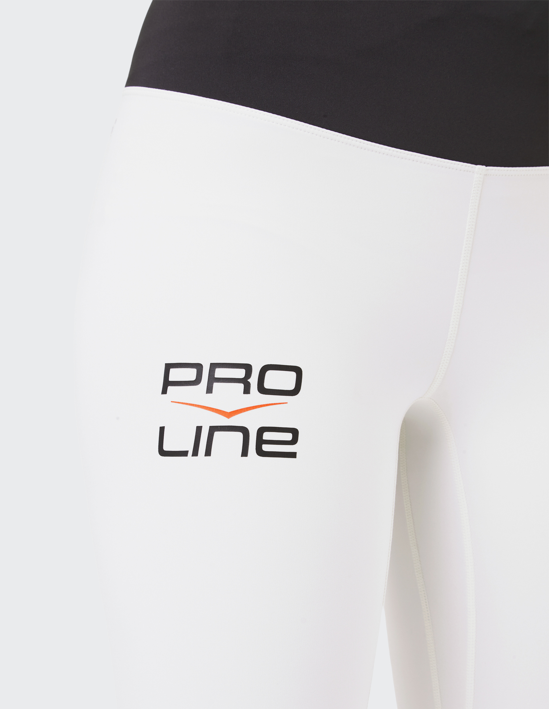 Nahaufnahme einer weißen Sportleggings mit schwarzem Bund und dem schwarzen Schriftzug PRO LINE mit orangem Akzent auf dem Oberschenkel.