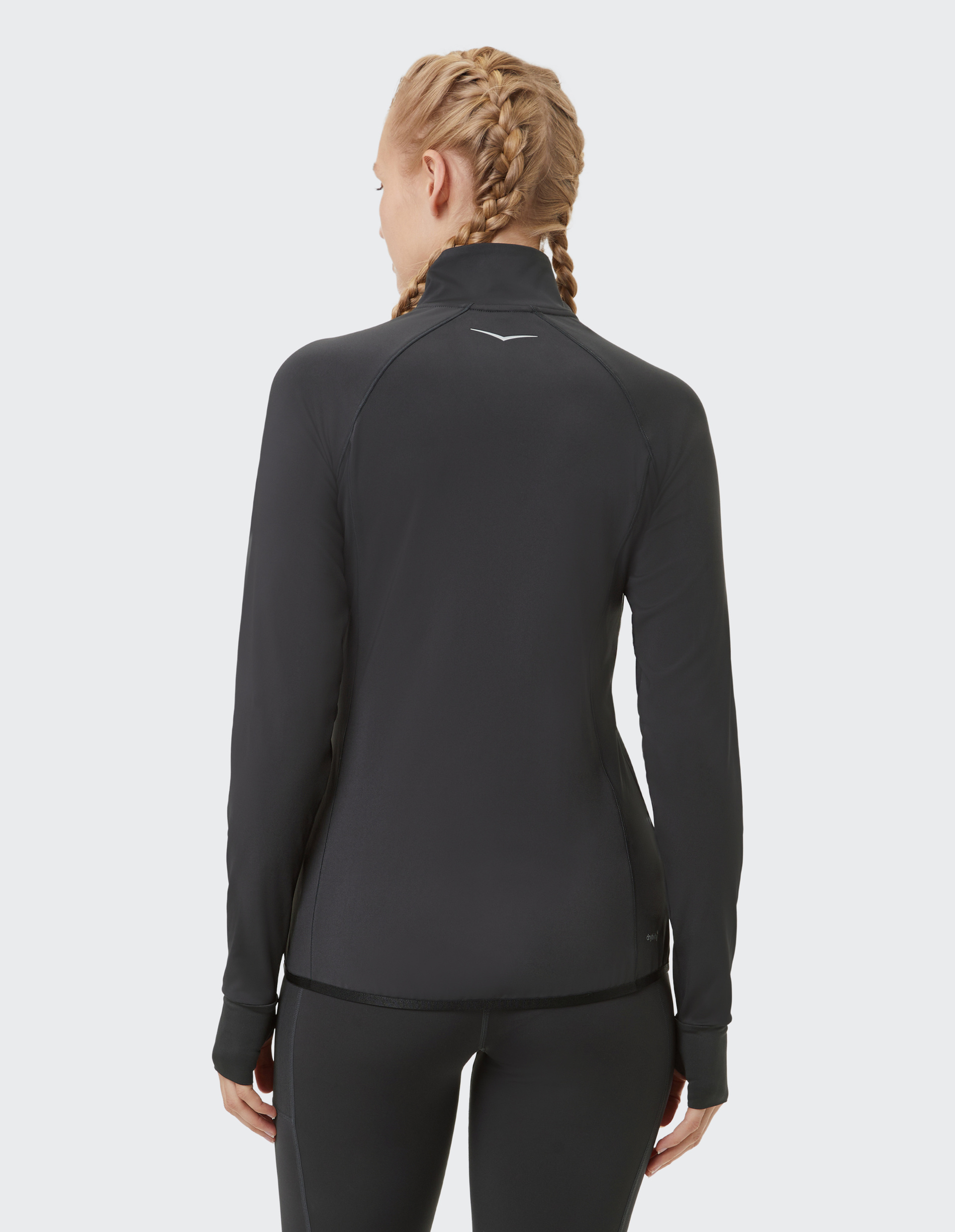 Eine Person mit geflochtenem Haar trägt eine schwarze, langärmelige Sportjacke mit Logo auf dem Rücken.