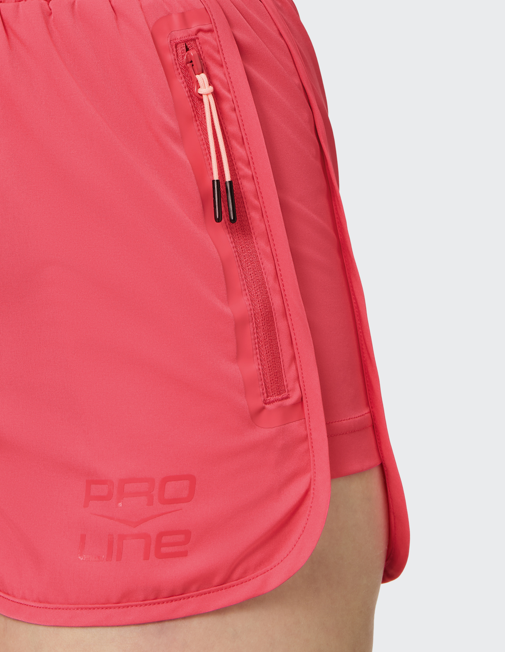 Nahaufnahme einer pinken Sportshorts mit elastischem Bund, seitlichem Reißverschluss und aufgedrucktem "Pro Line"-Logo am Saum.