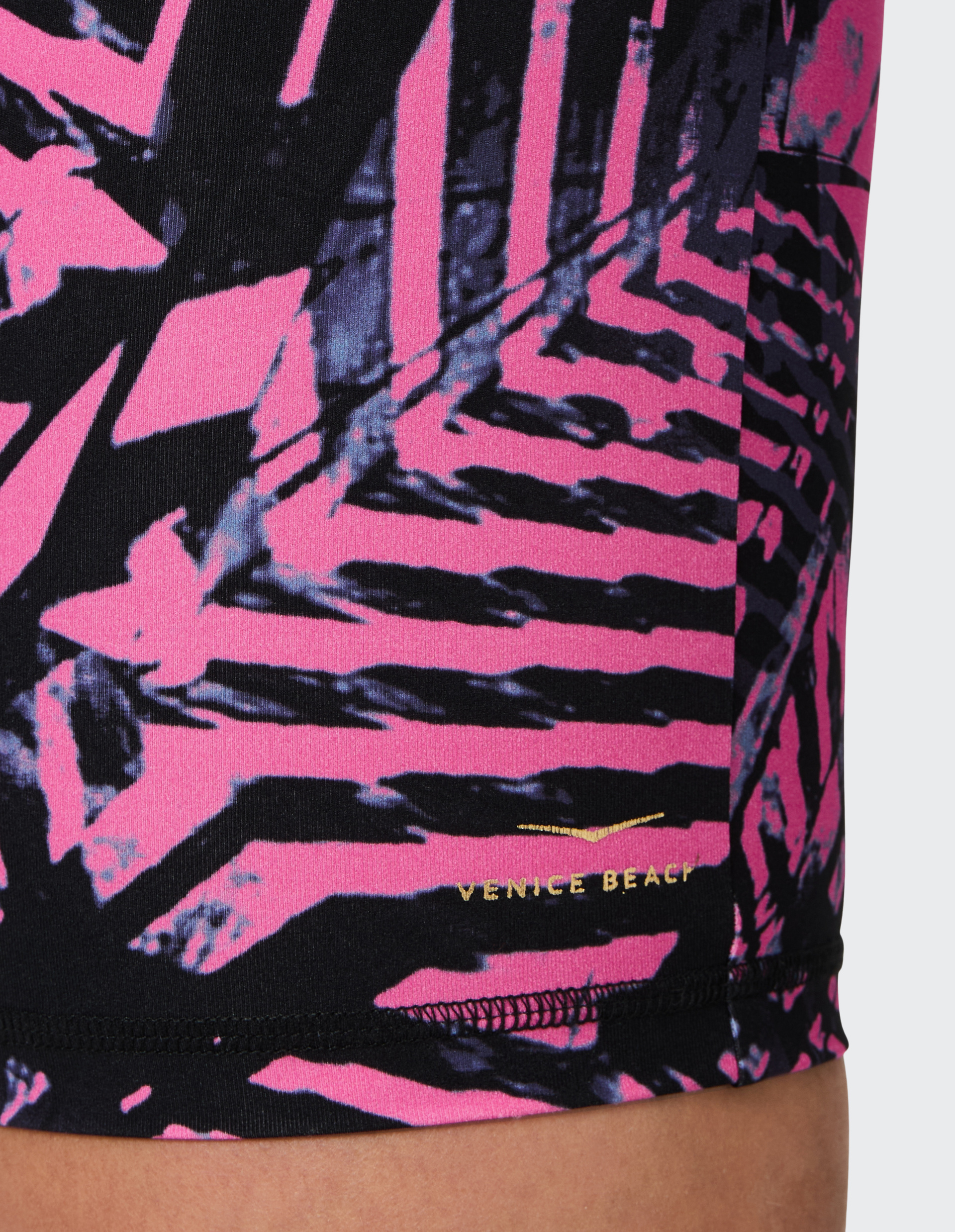 Nahaufnahme eines elastischen Stoffs mit rosa und schwarzen Zickzackmustern und dem goldenen Aufdruck "Venice Beach".