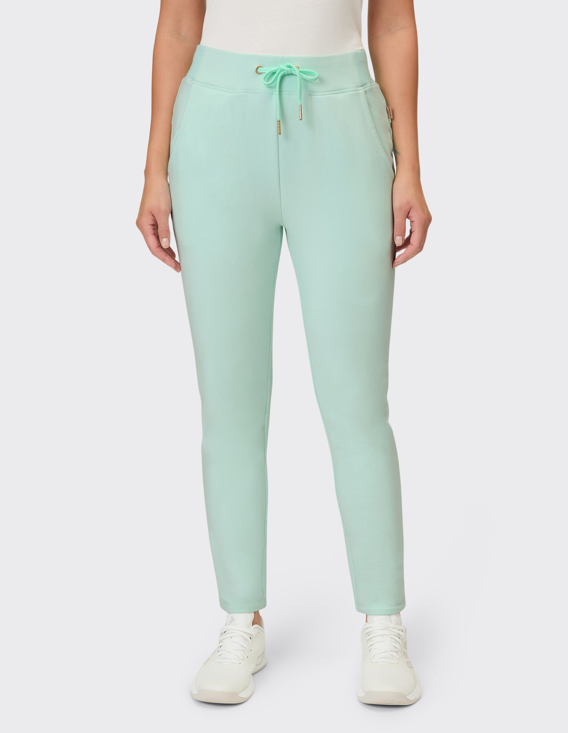 Eine Person trägt eine mintgrüne Hose mit Kordelzug und weißen Sneakers.