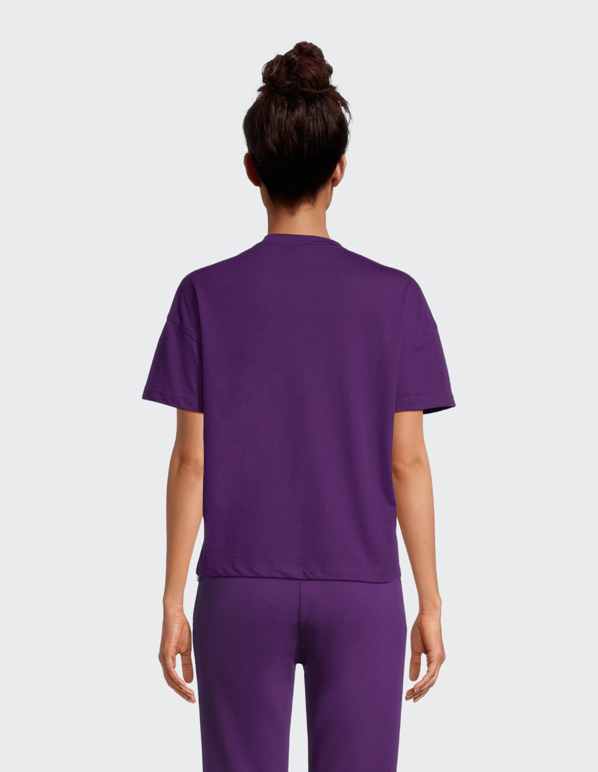 Die Rückseite einer Person trägt ein schlichtes, violettes T-Shirt und passende violette Hosen.