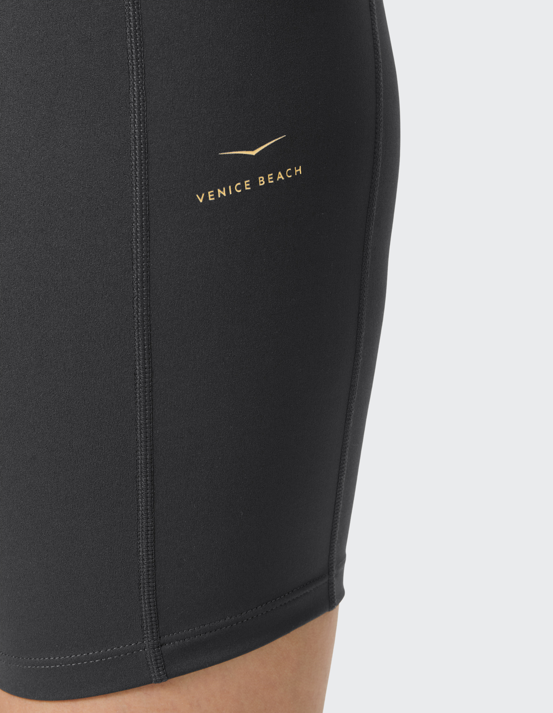 Schwarze eng anliegende Sportleggings mit gelbem "Venice Beach"-Logo an der Seite, fokussiert auf den Oberschenkelbereich.