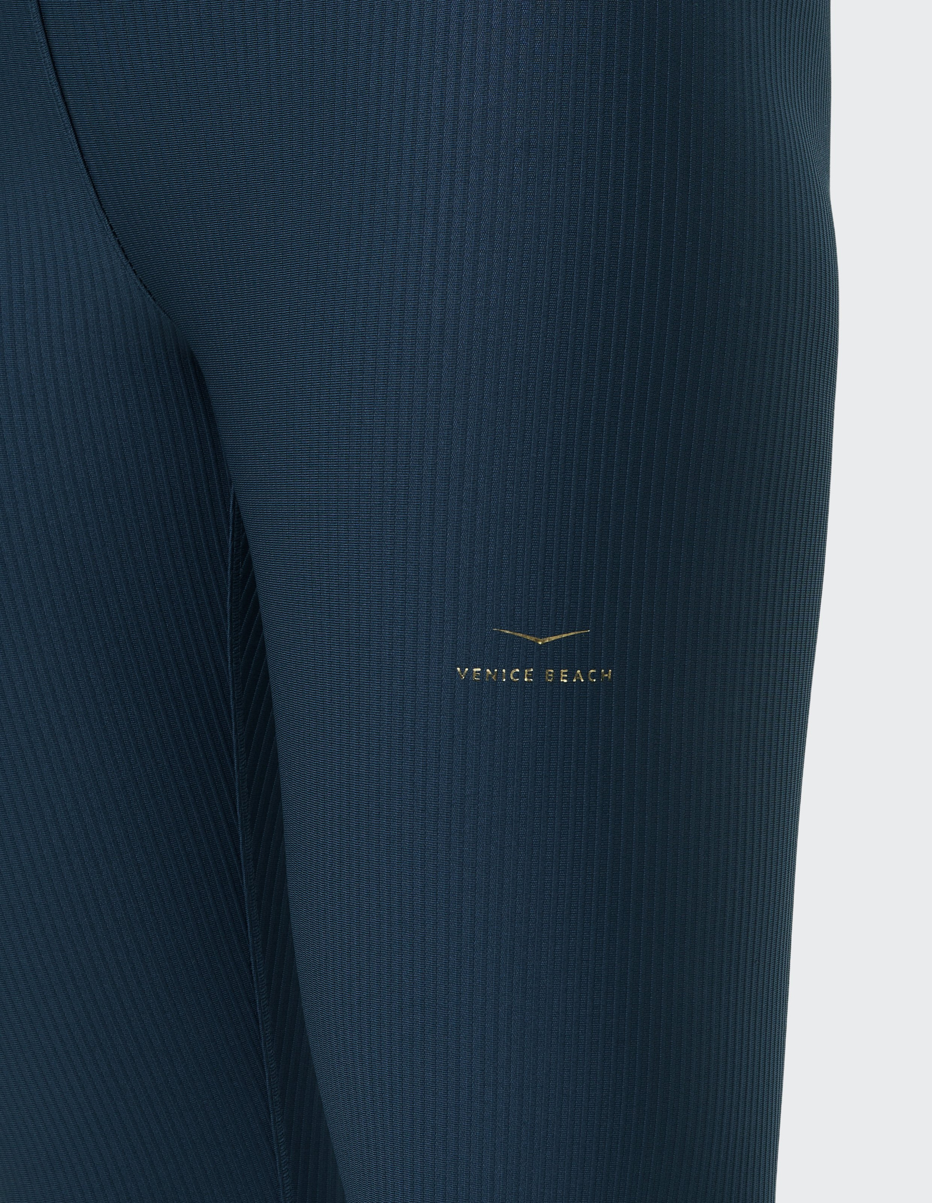 Dunkelblaue, rippstrukturierte Leggings mit kleinem, goldenem "Venice Beach"-Logo seitlich auf dem Oberschenkel.
