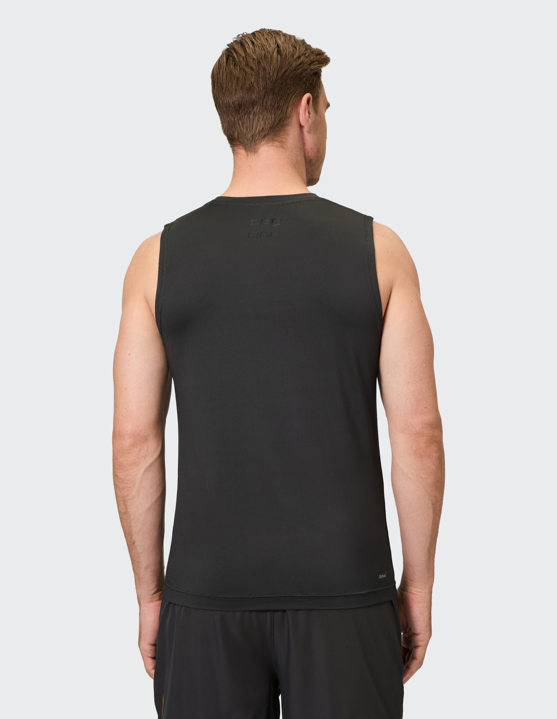 Ein Mann von hinten in einem schwarzen ärmellosen Shirt und schwarzen Shorts, steht vor neutralem Hintergrund.