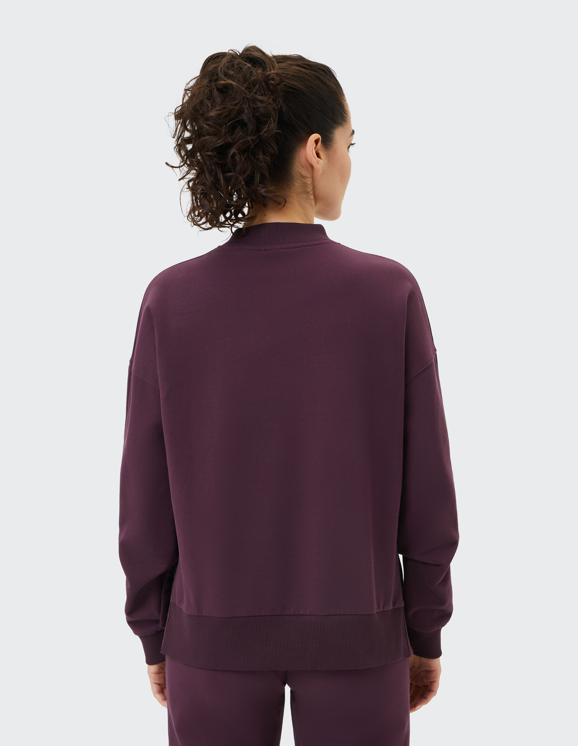 Ein dunkelvioletter Pullover mit langen Ärmeln und rundem Hals, gefertigt aus weichem Stoff, mit elastischen Bündchen.