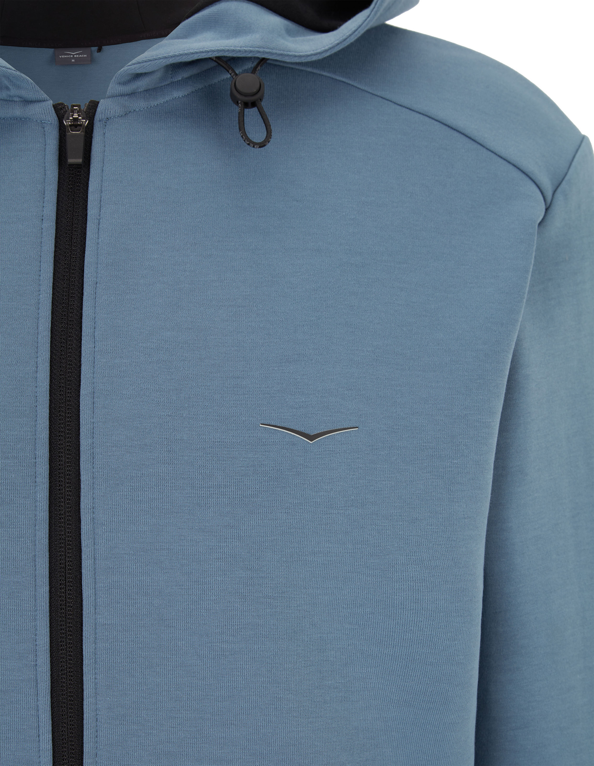 Blau-grauer Hoodie mit Kapuze und schwarzem Reißverschluss; dezentes Logo auf der Brust und Kordelzug-Detail am Kragen.