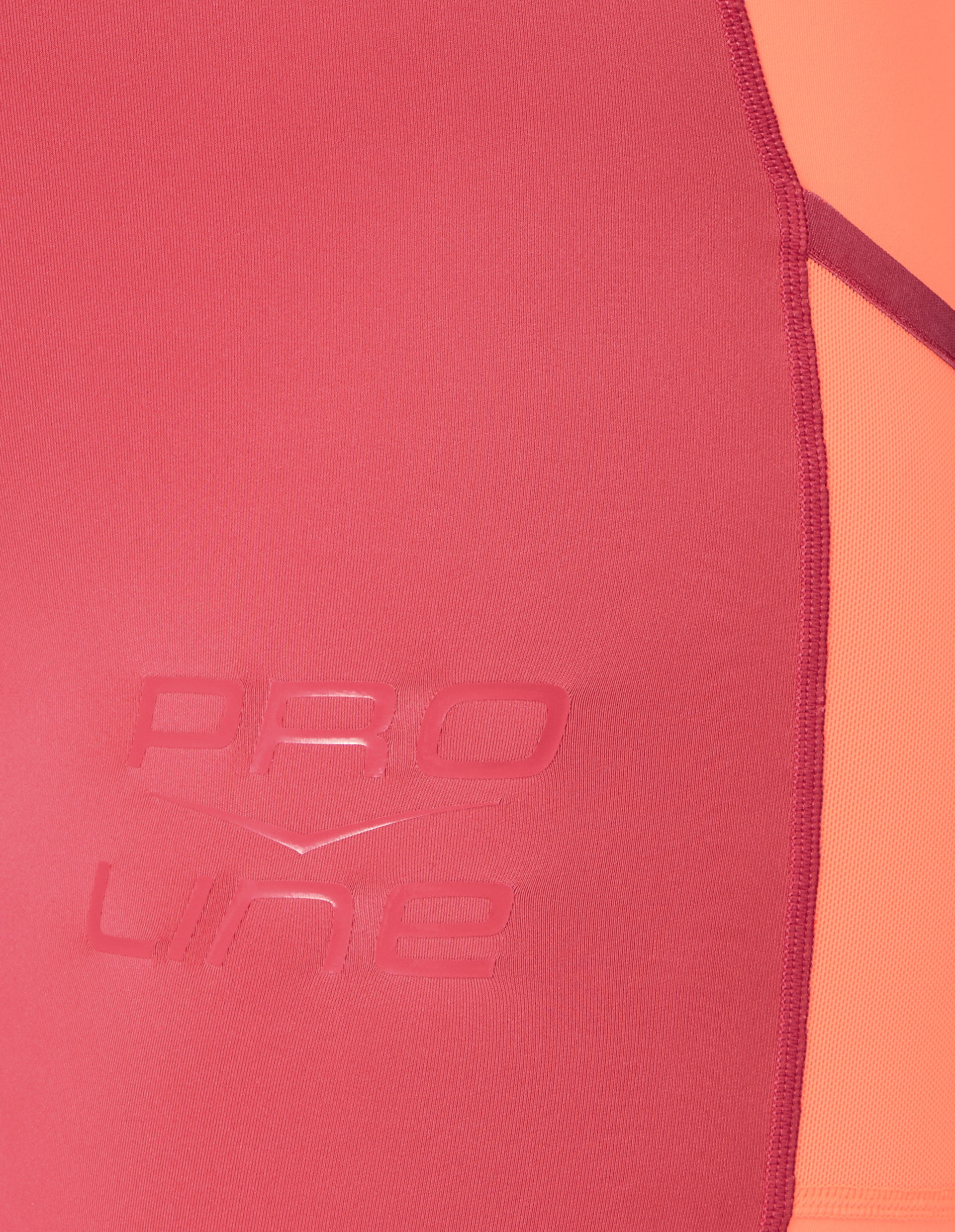 Nahaufnahme eines sportlichen, nahtlosen Stoffes in Rot mit orangefarbener Seitenfläche und eingeprägtem "PRO LINE"-Logo.