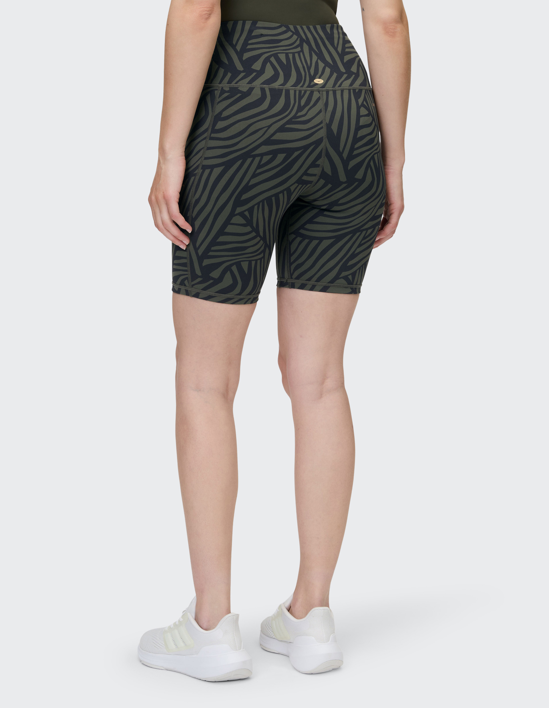 Kurze Leggings mit hohem Bund in Olivgrün, verziert mit einem abstrakten, schwarzen Streifenmuster, das an Zebramuster erinnert.