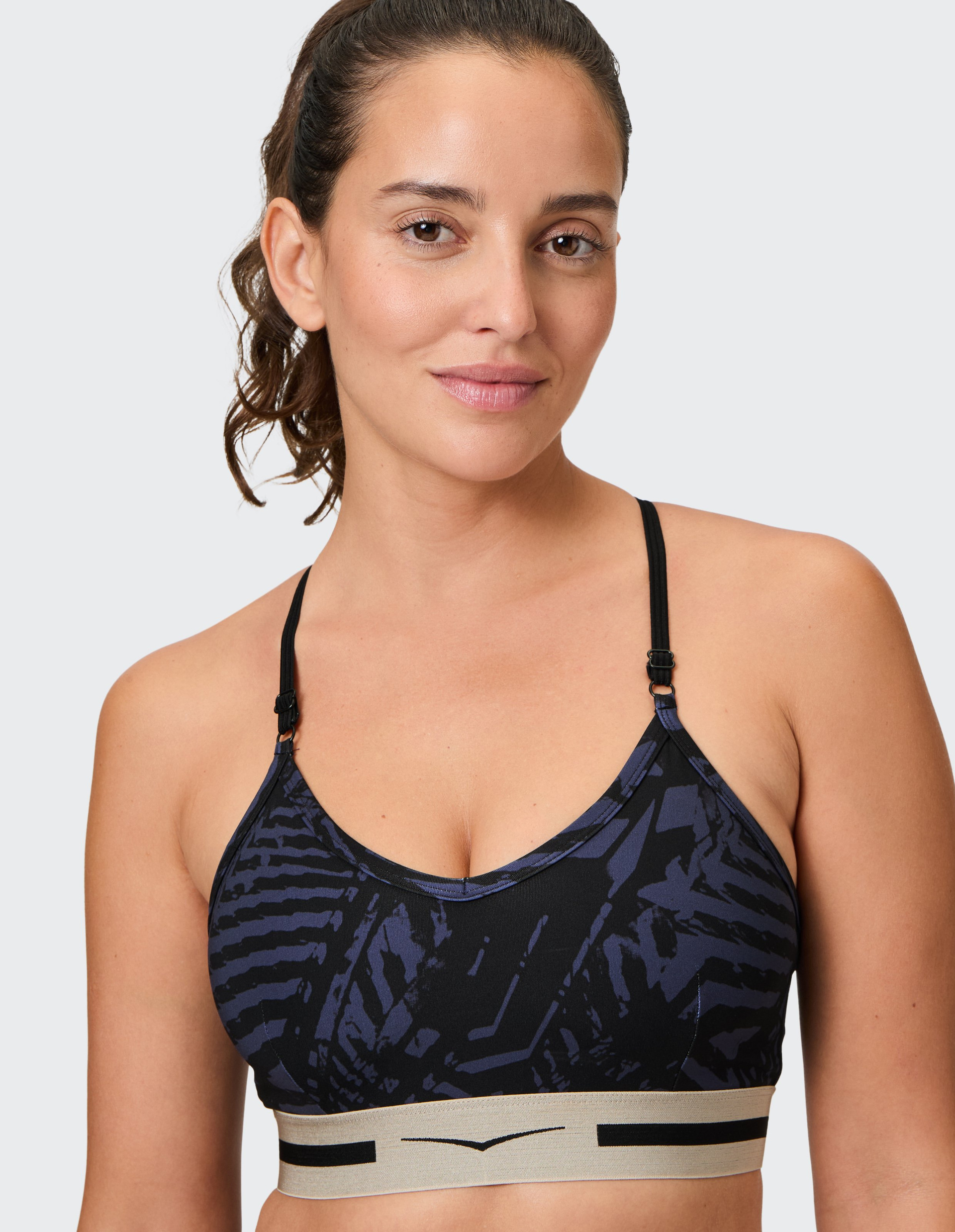 Sport-BH mit dunkelblauem, abstraktem Muster, verstellbaren Trägern und beige-schwarzem elastischem Unterband für sicheren Halt.