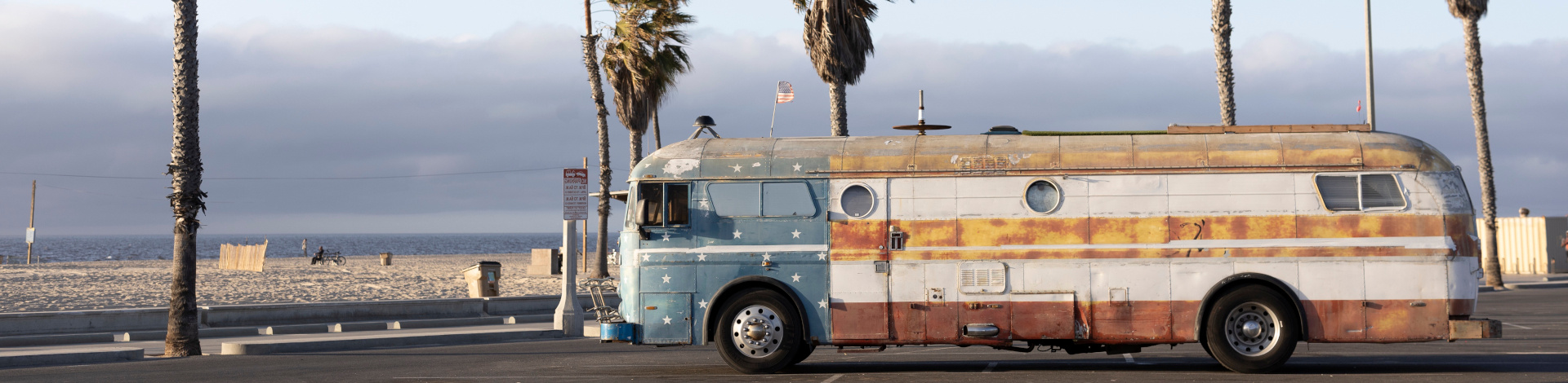 Bus steht am Strand vor Palmen.