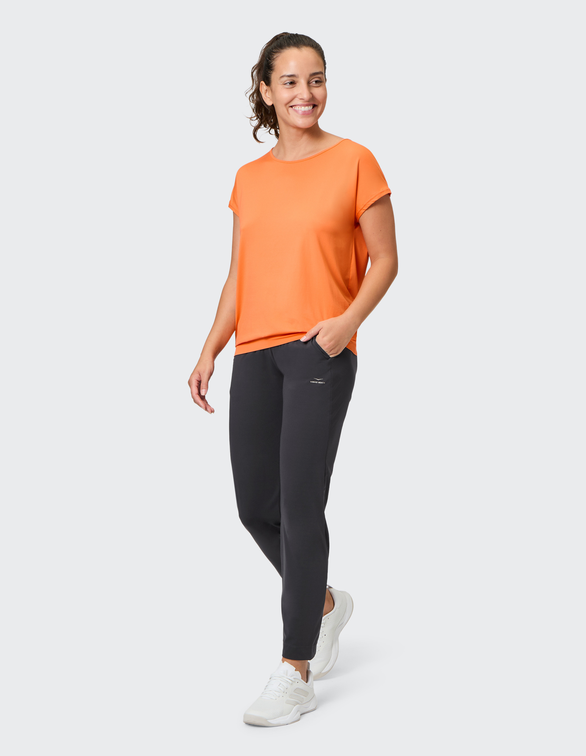 Dunkelgraue, schmal geschnittene Hose aus glattem Stoff mit dezenter Logo-Stickerei auf dem linken Oberschenkel, ohne sichtbaren Verschluss.