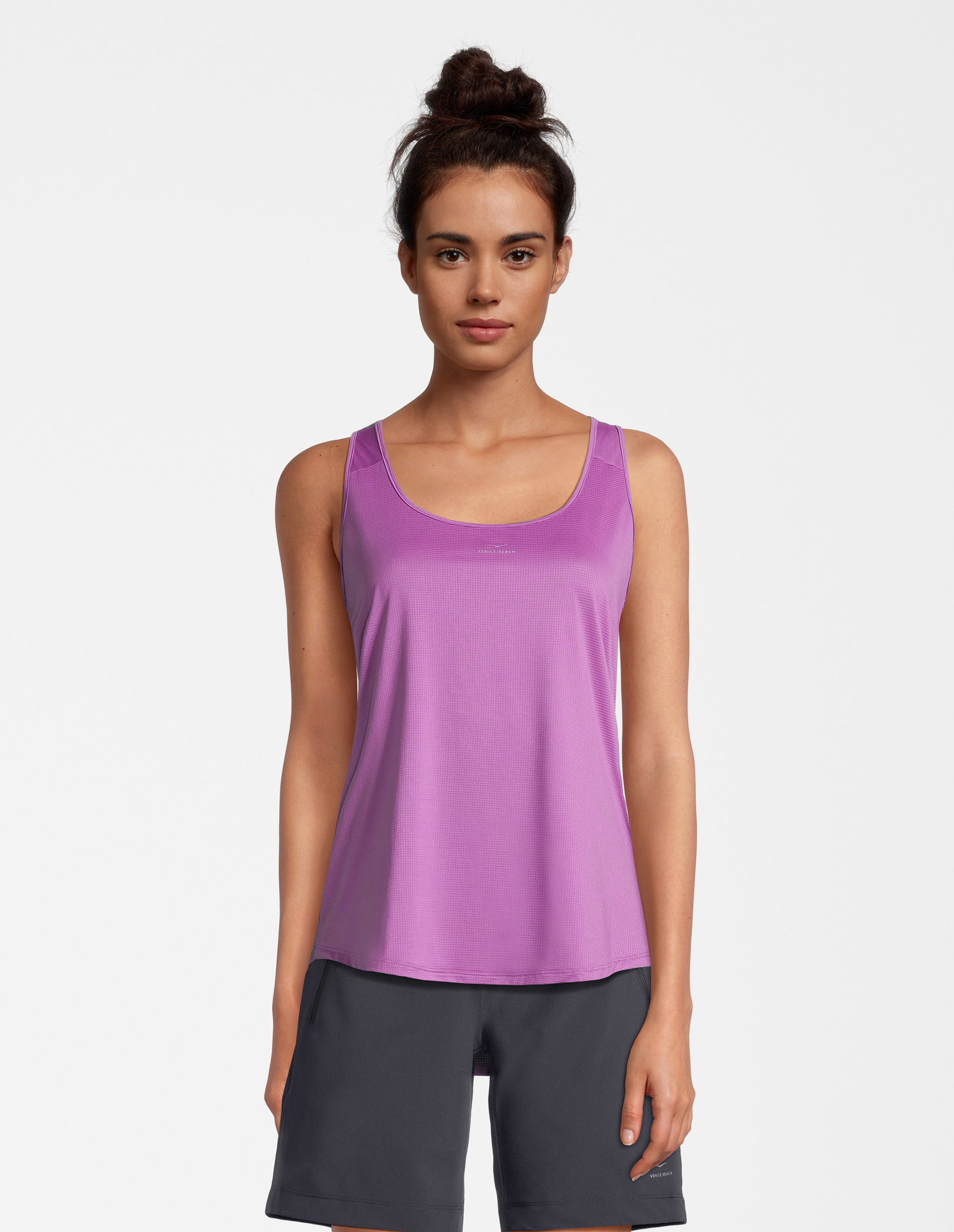 Eine Frau trägt ein lilafarbenes Sport-Top mit U-Ausschnitt und eine dunkelgraue Shorts.