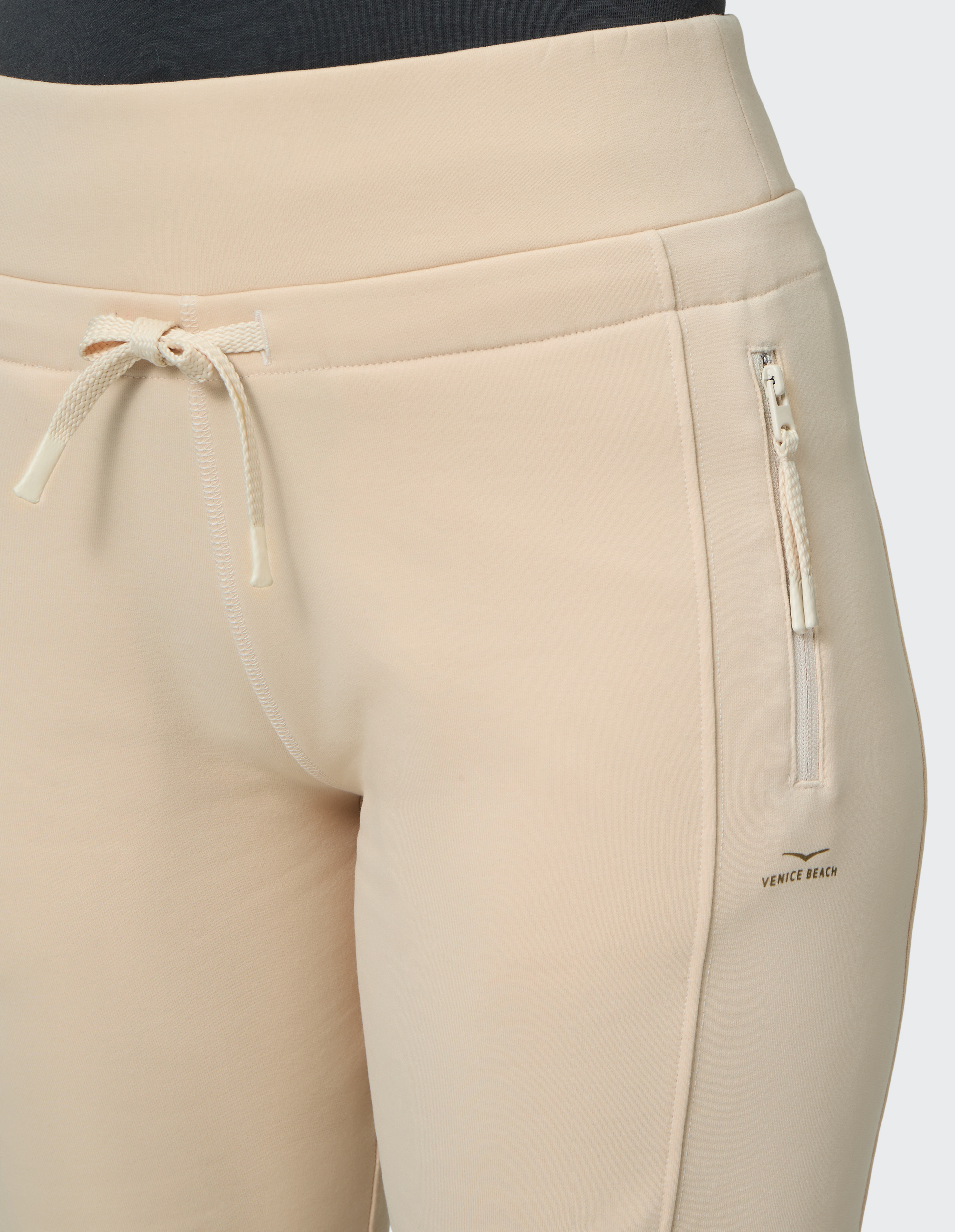 Beige Jogginghose mit Kordelzug und Reißverschlusstasche an der Seite, auf der "Venice Beach" in kleiner Schrift steht.