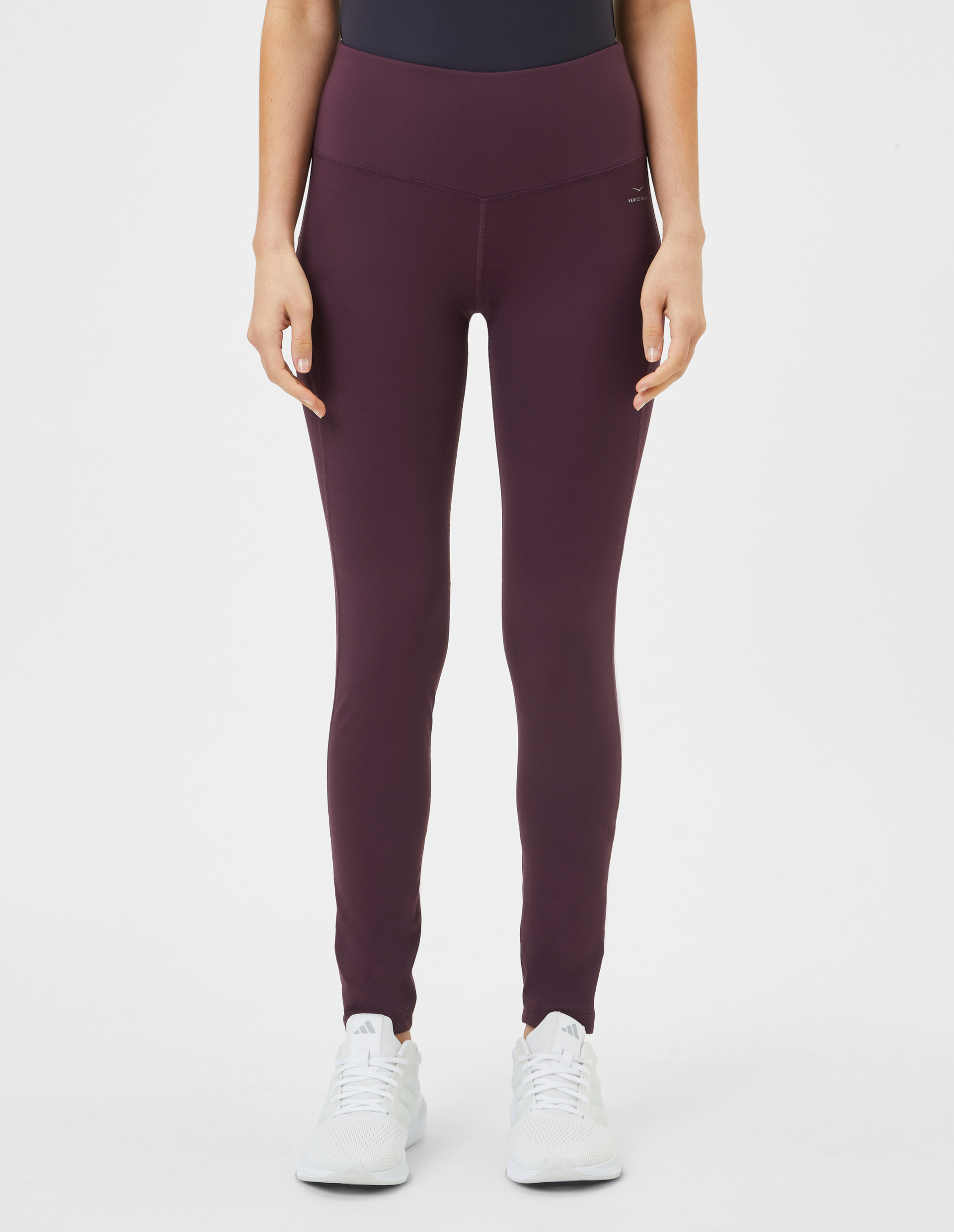Dunkellila Leggings mit hohem Bund und langem Schnitt; nahtlose Struktur und dezentes Logo oberhalb des rechten Oberschenkels.