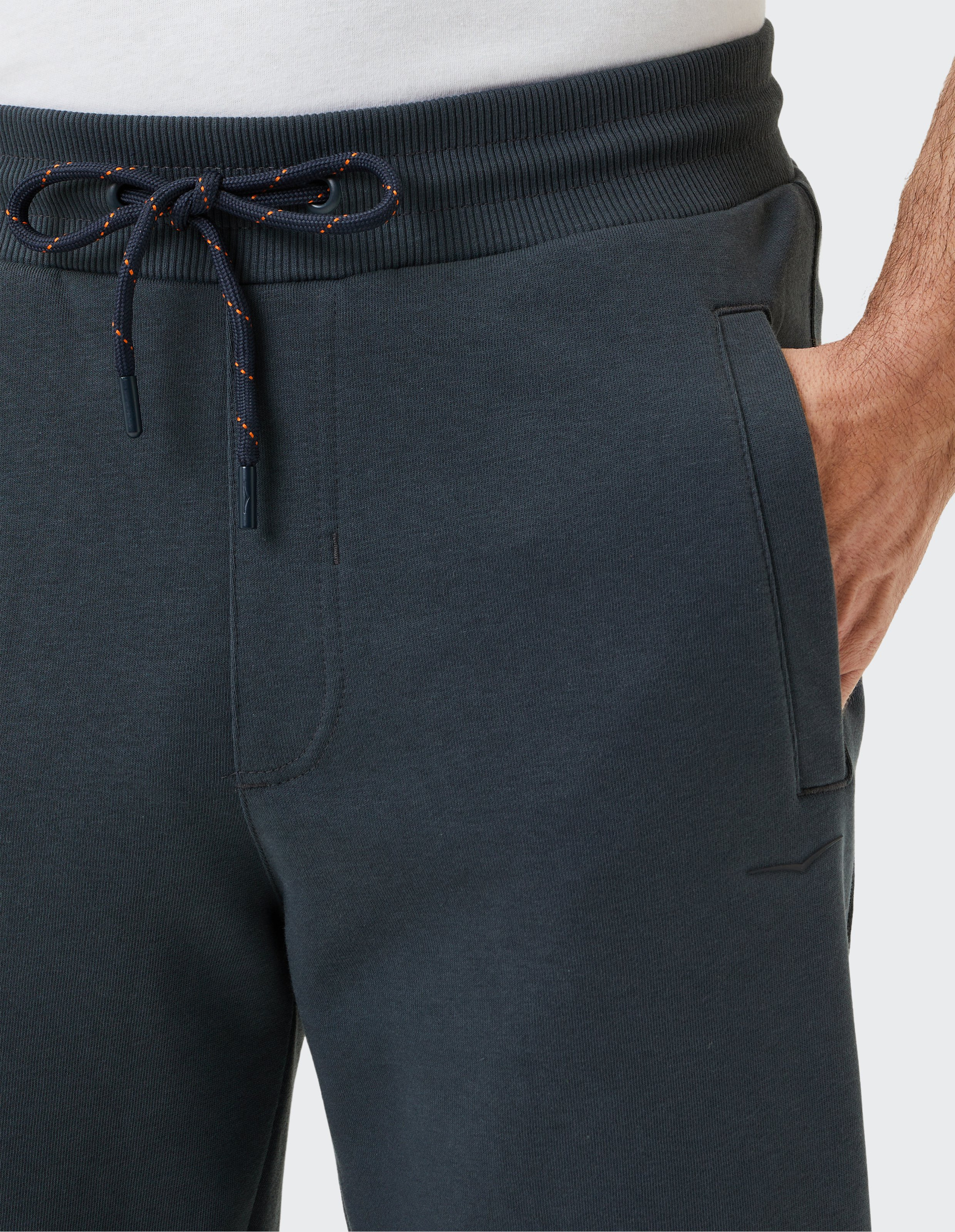 Dunkelblaue Jogginghose mit elastischem Bund, dekorativer Kordel und seitlicher Eingrifftasche, getragen von einer Person in weißem Shirt.