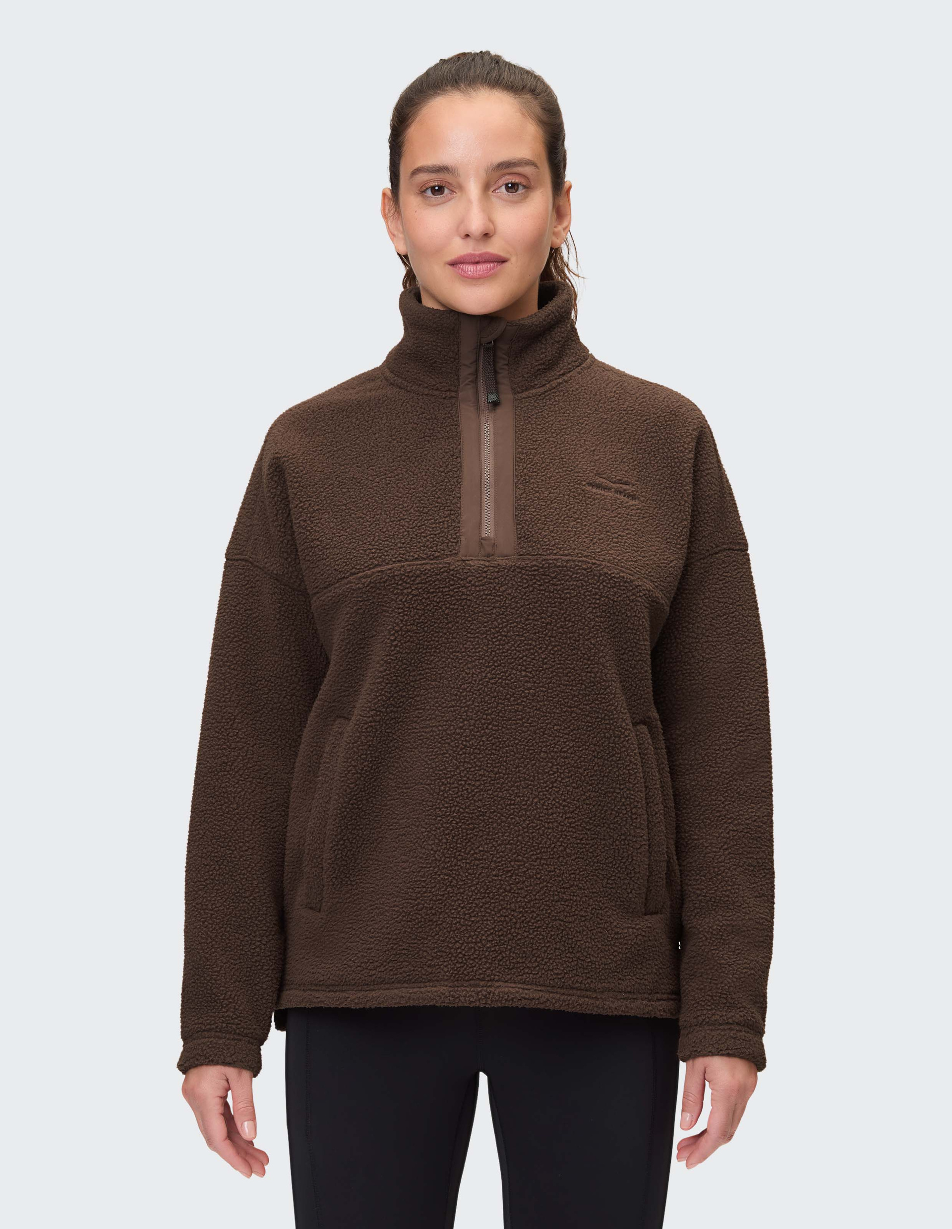 Brauner Fleecepullover mit hohem Kragen und kurzem Reißverschluss, vorderseitige Taschen und weicher, strukturierter Stoff.