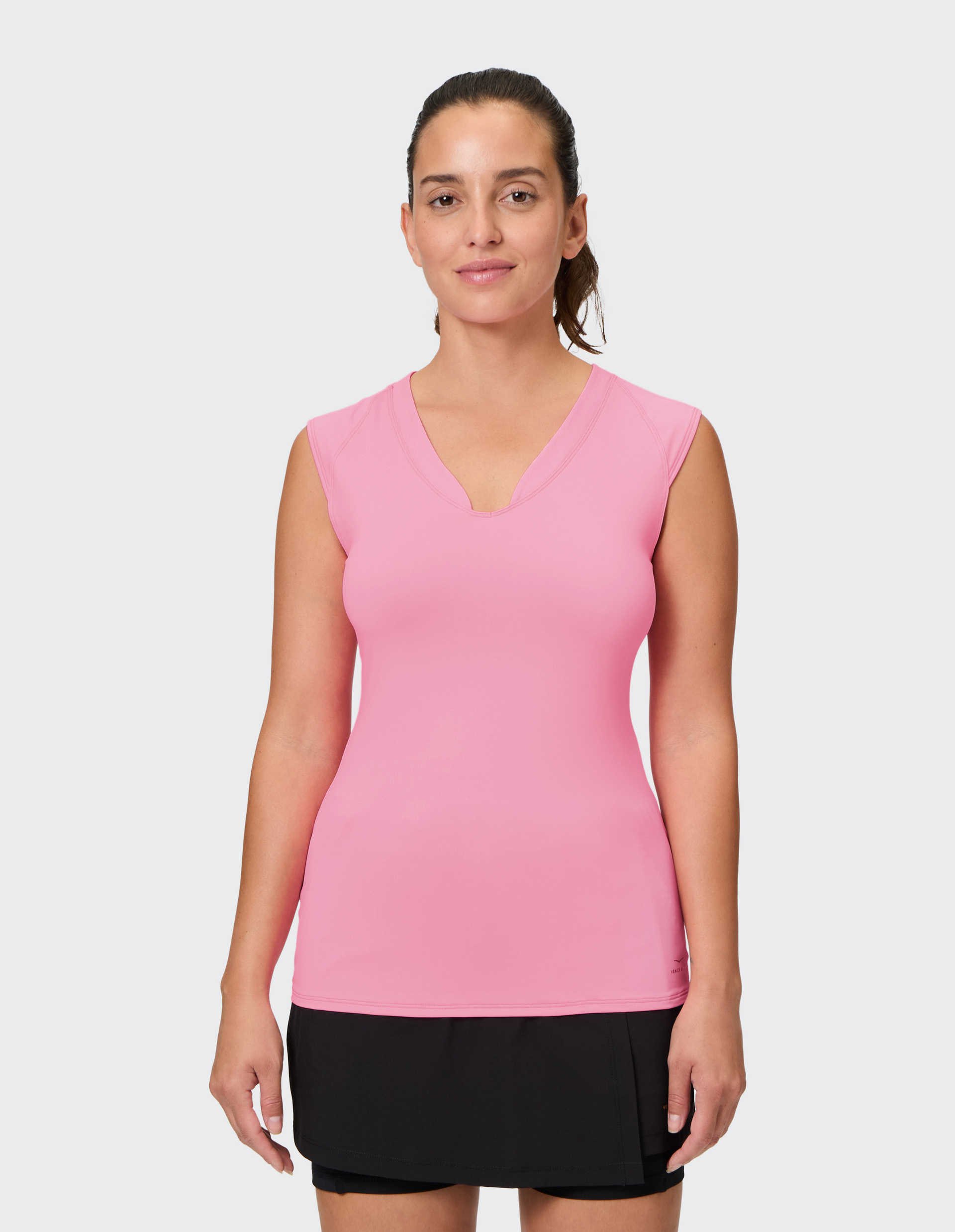 Frau mit rosa ärmellosem Shirt und schwarzem Rock, lächelt dezent vor weißem Hintergrund.