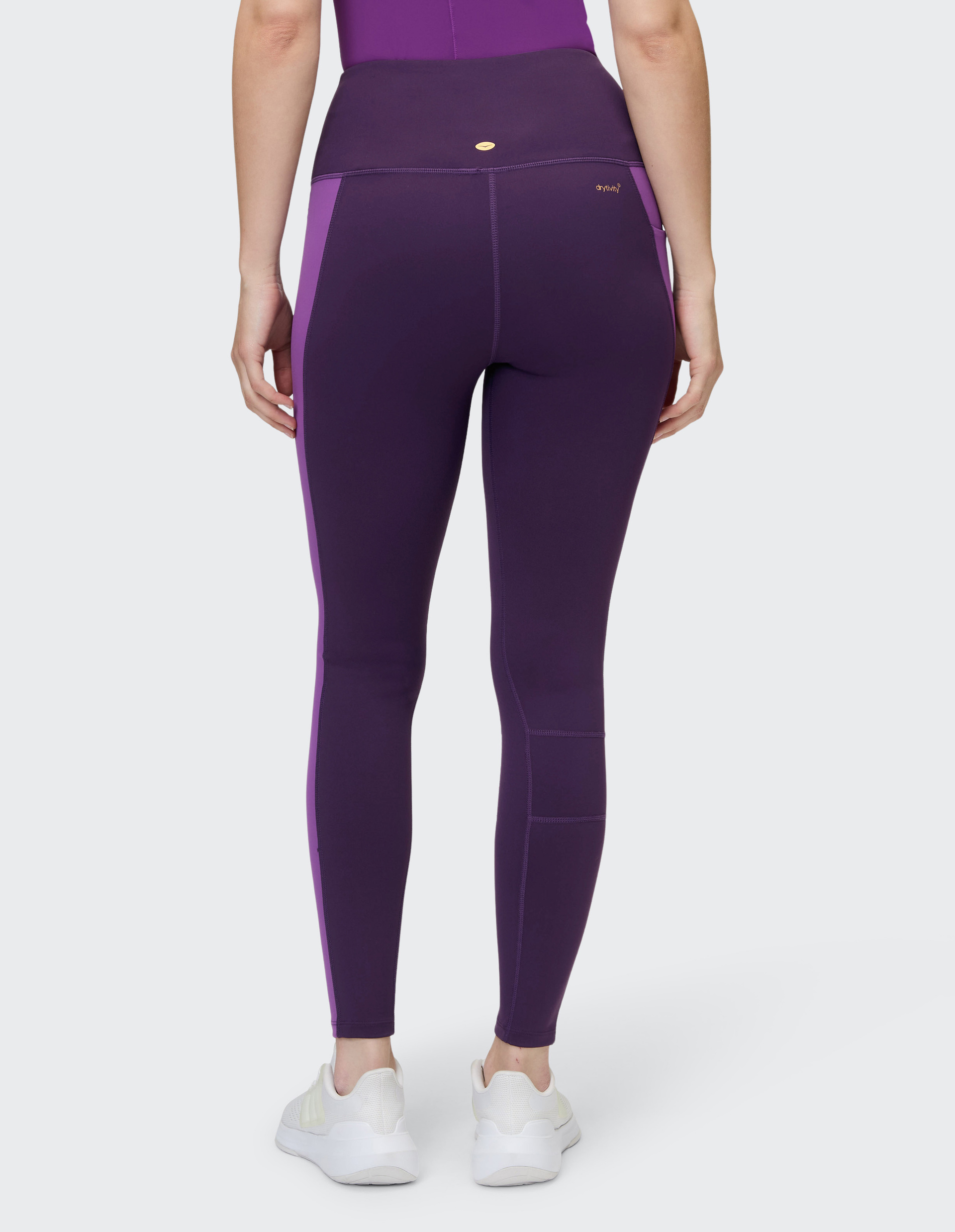 Dunkellila Leggings mit kontrastierenden helleren lila Seitenstreifen, hoher Taille und einer Tasche am Oberschenkel.