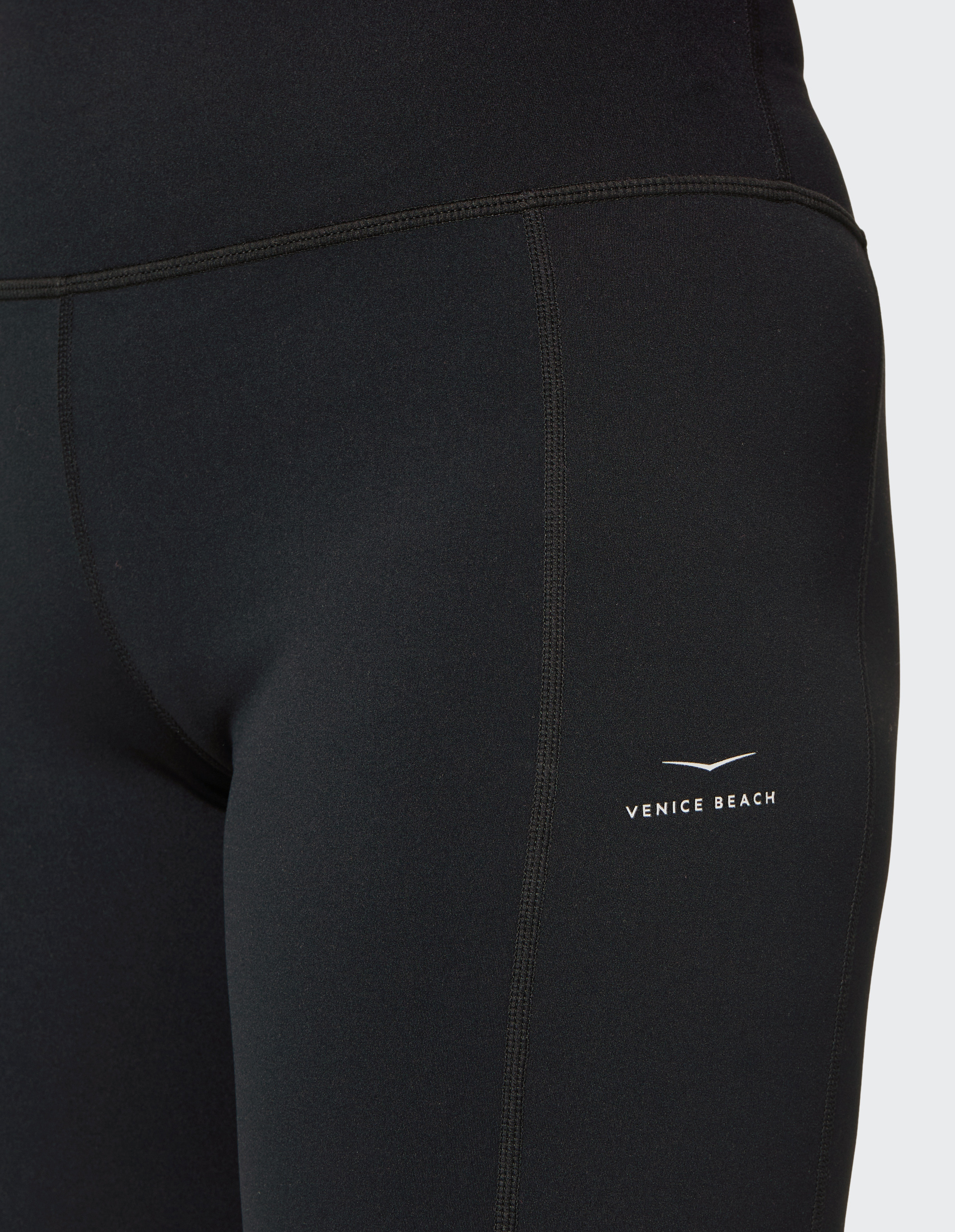 Nahaufnahme einer schwarzen Sportleggings mit weißem Venice Beach-Logo auf der Hüfte, Nähte betonen den figurbetonten Schnitt.