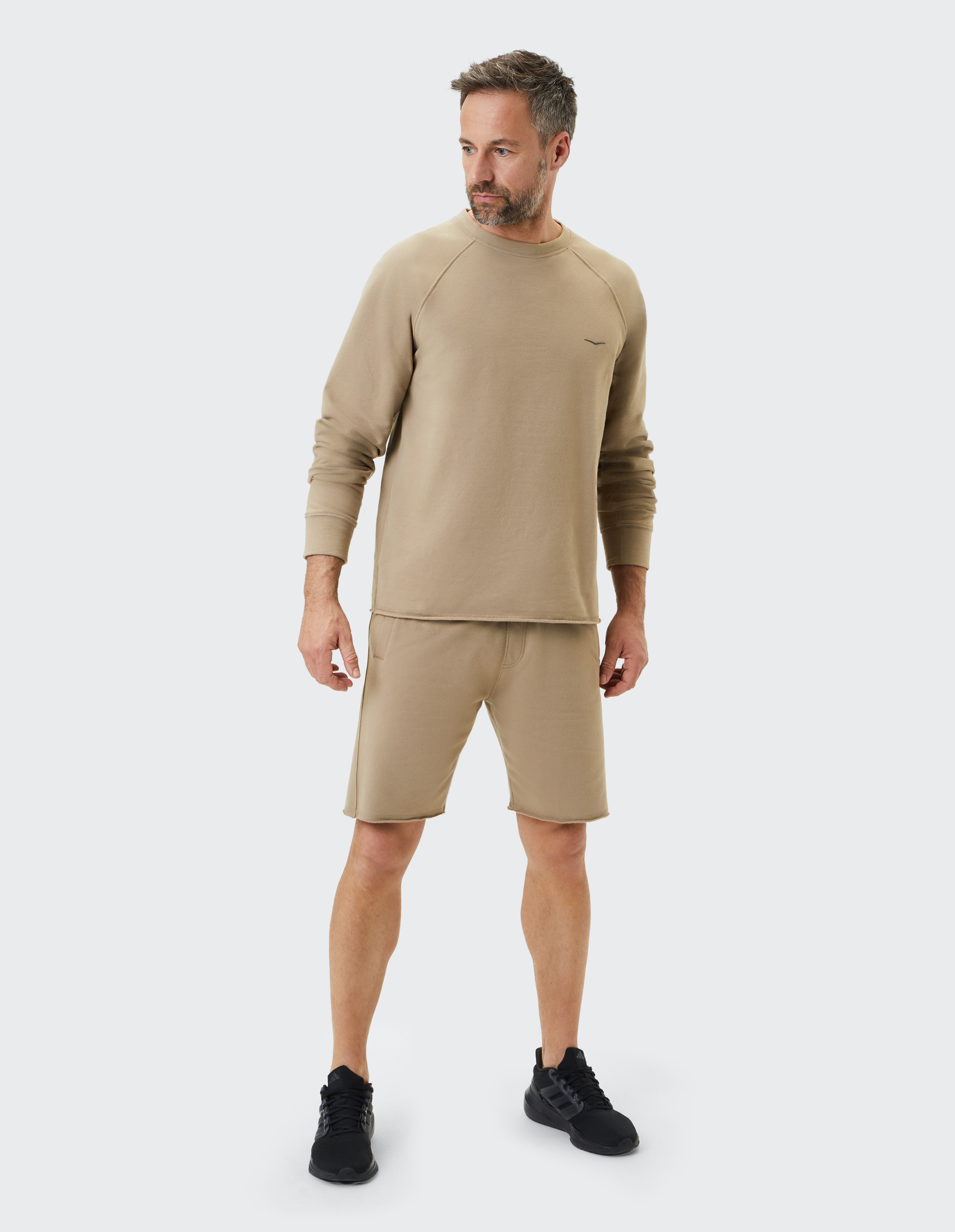 Beigefarbener Pullover mit Rundhalsausschnitt und kleinem aufgesticktem Logo auf der Brust, mit langen Ärmeln und geradem Schnitt.